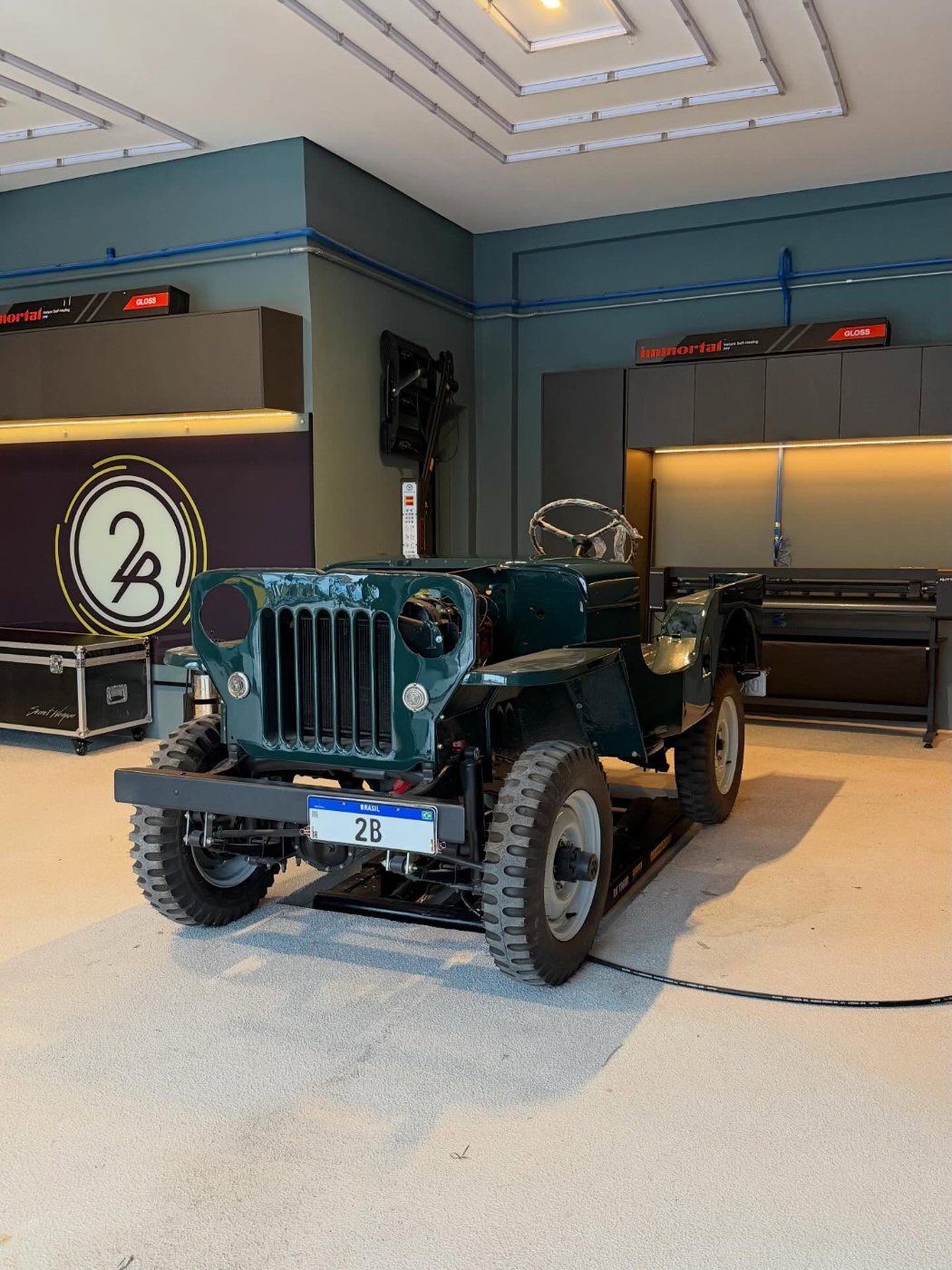 Jeep Willys 1952 verde dentro da loja, com o logo 2B na parede